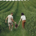 Happy family walking together through a lush green field enjoying nature and togetherness.